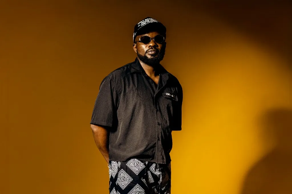 Ally Fresh in black shirt and sunglasses against a mustard yellow backdrop