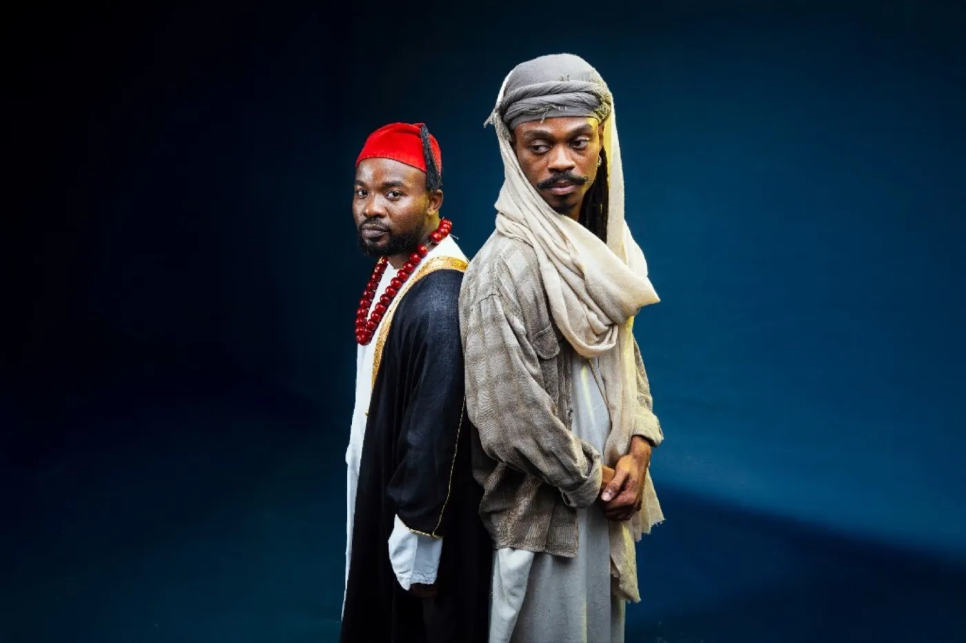 Ally Fresh and collaborator in traditional attire, studio portrait back-to-back