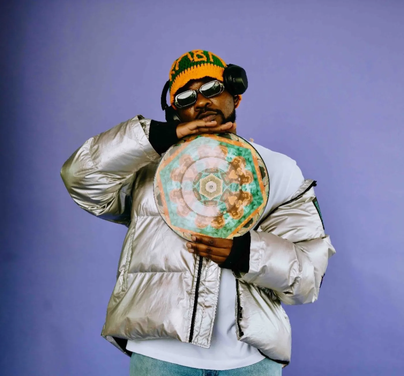 Ally Fresh in silver jacket holding a vinyl record, studio portrait